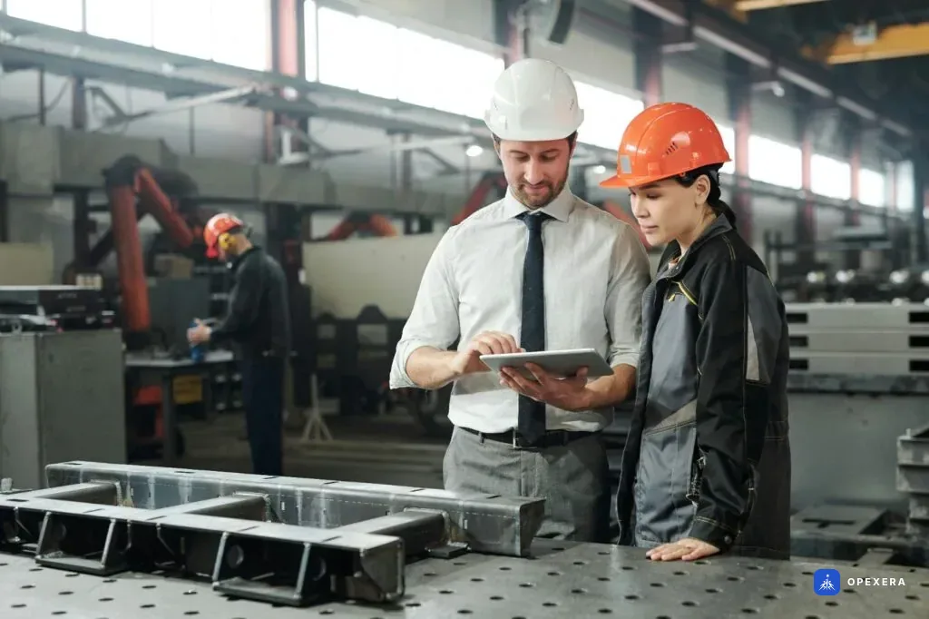 Fabrikada tablet üzerinden üretim verisini birlikte inceleyen mühendis ve saha çalışanı